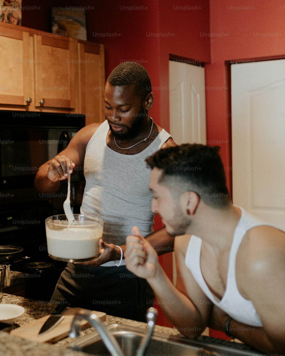 two men in a kitchen mixing a mixture together