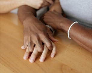 Eine Nahaufnahme von zwei Personen, die sich auf einem Tisch an den Händen halten