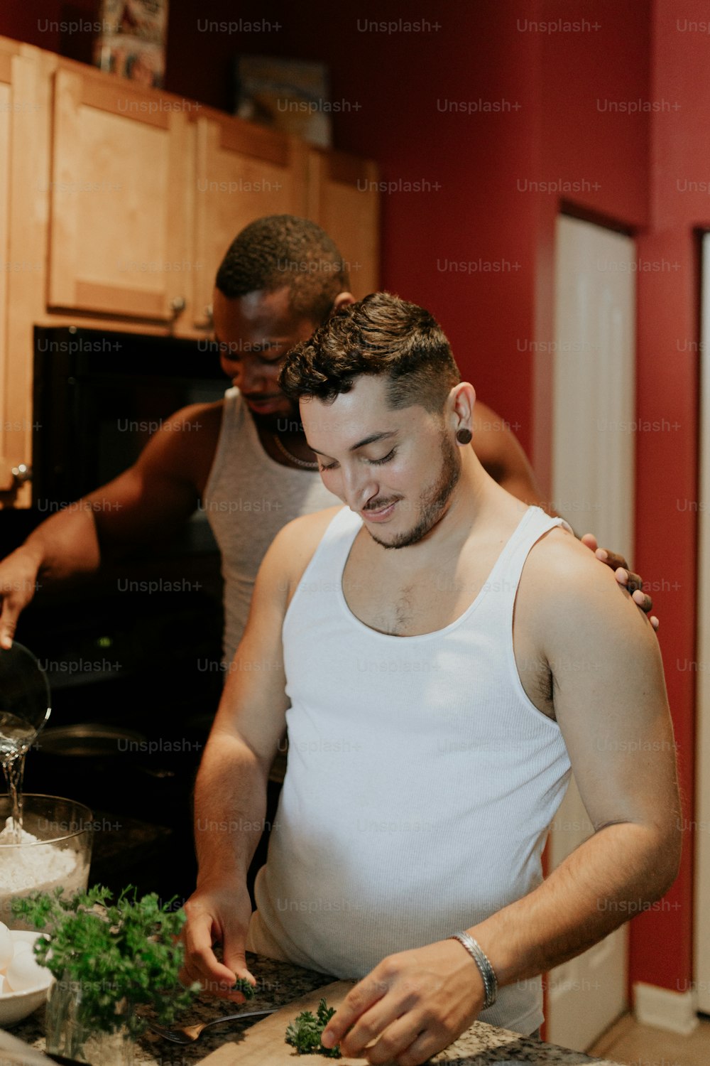 a couple of men standing in a kitchen preparing food