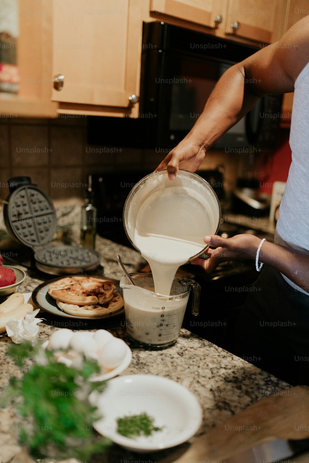 a woman pours milk into a bowl on a kitchen counter