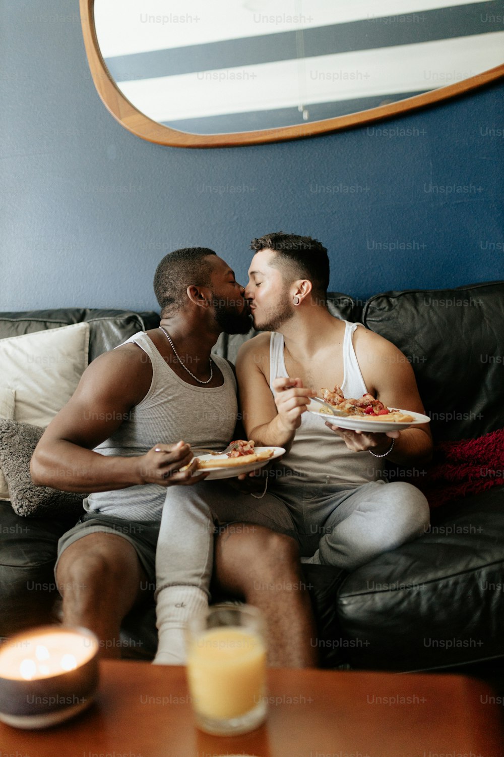 dois homens sentados em um sofá comendo pizza