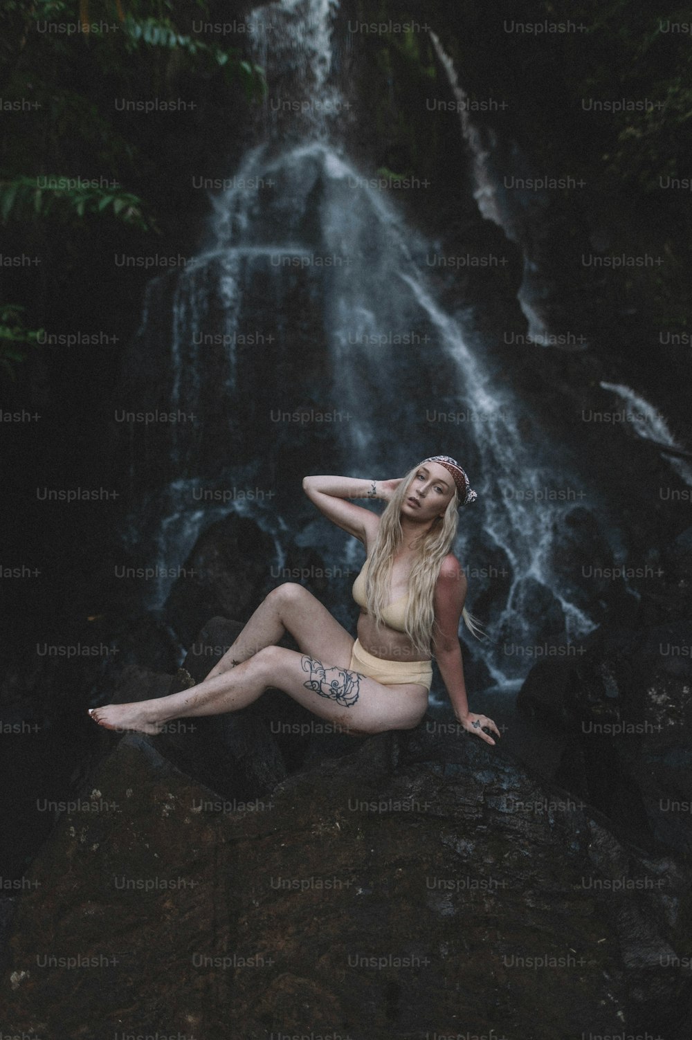 Una mujer sentada en una roca frente a una cascada