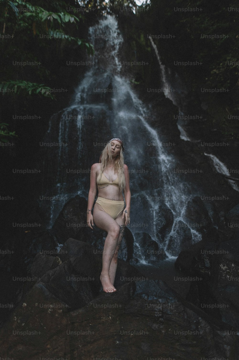 a woman in a bikini standing in front of a waterfall