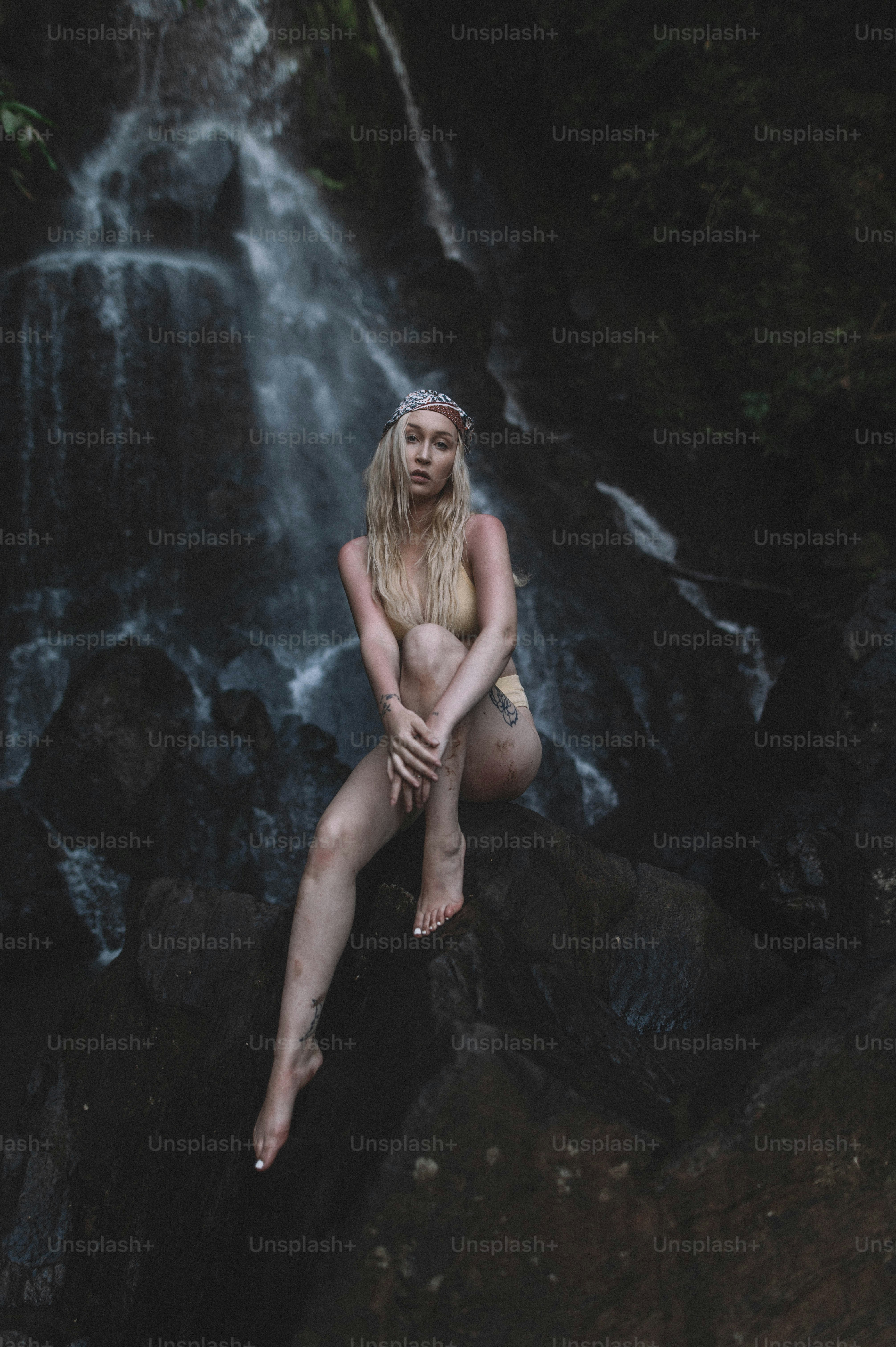 Eine Frau, die auf einem Felsen vor einem Wasserfall sitzt