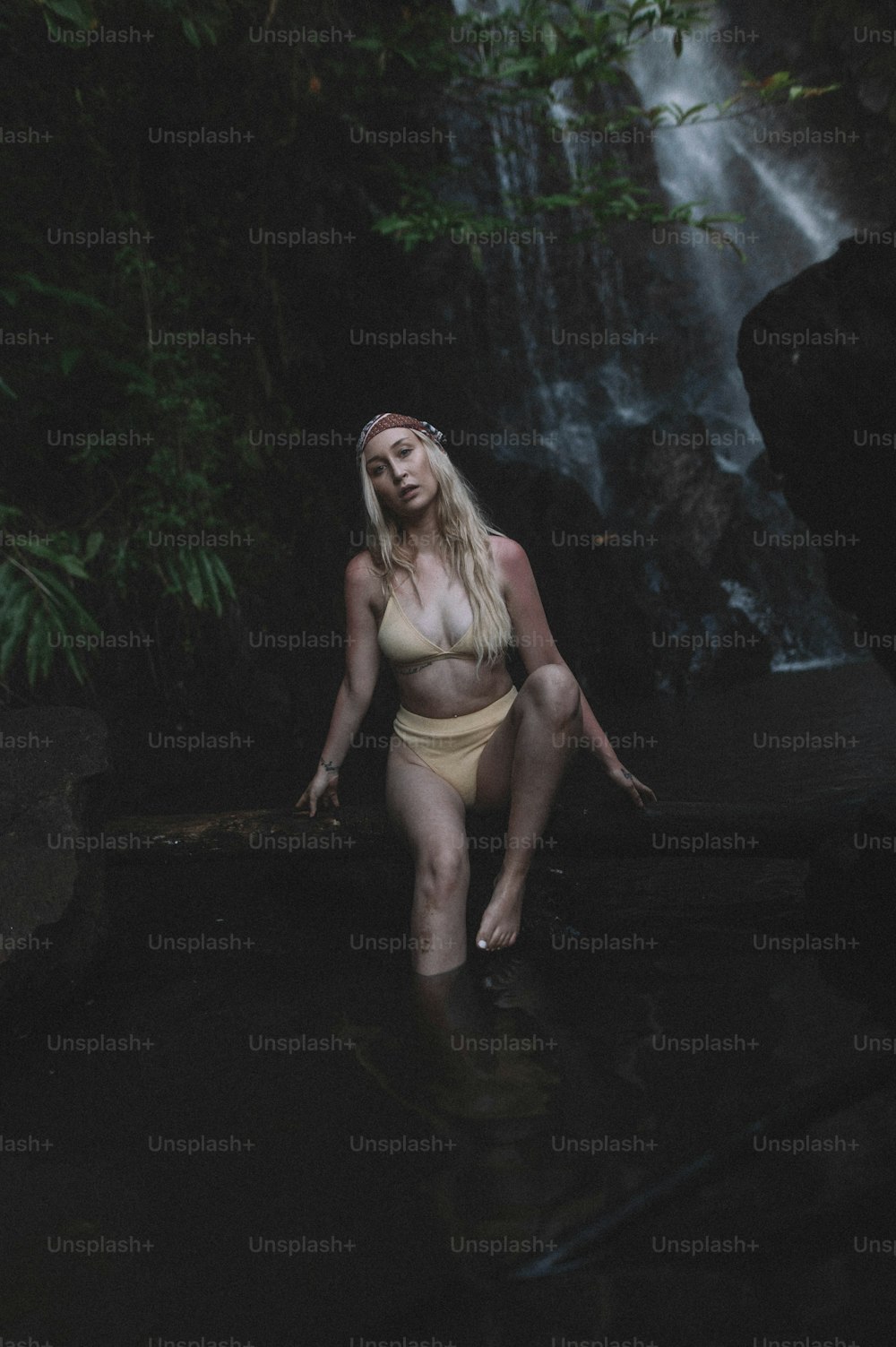 a woman in a bikini standing in the water near a waterfall