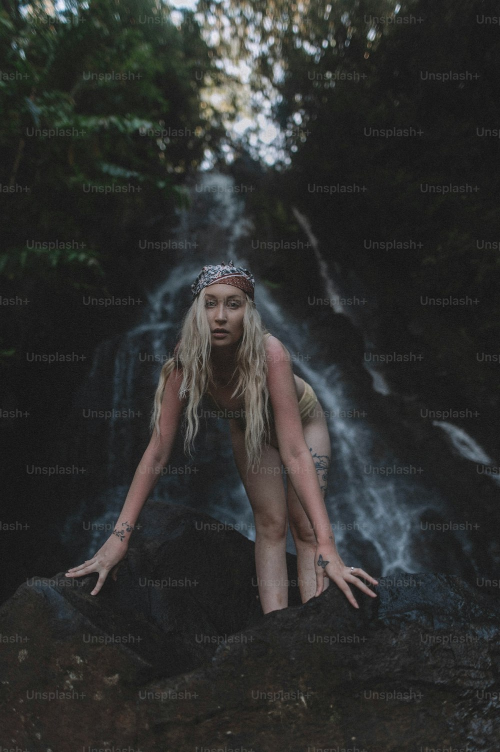 Una mujer está parada en una roca frente a una cascada