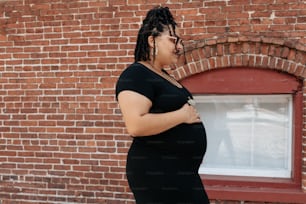 Eine schwangere Frau, die vor einem Backsteingebäude steht
