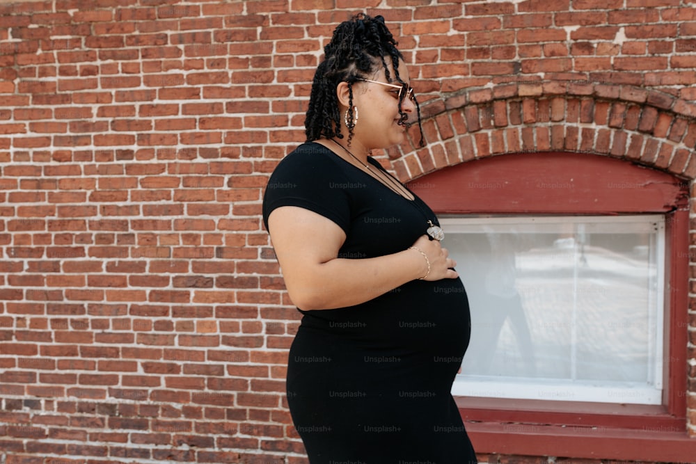 a pregnant woman standing in front of a brick building
