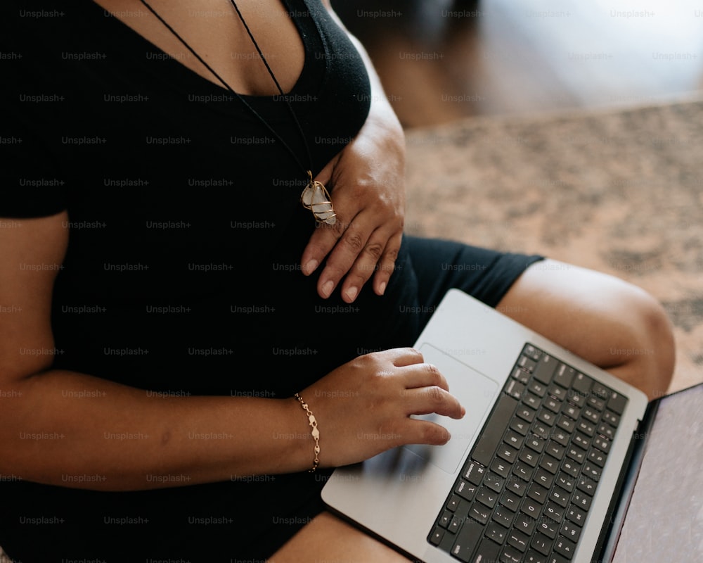 ノートパソコンを使って床に座っている妊婦
