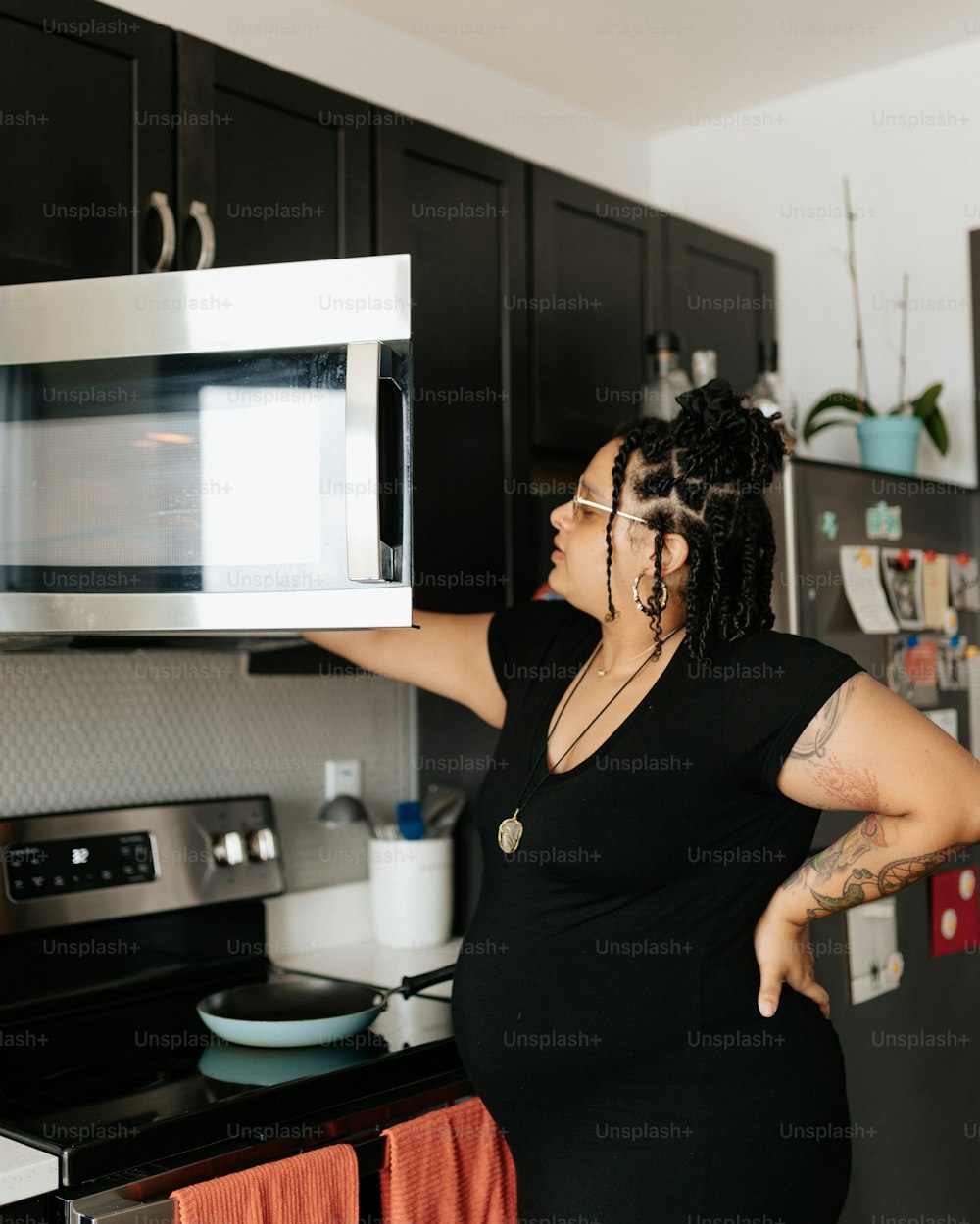 a woman in a black dress is holding a microwave
