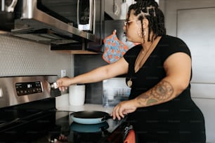 a woman in a black shirt is cooking in a kitchen