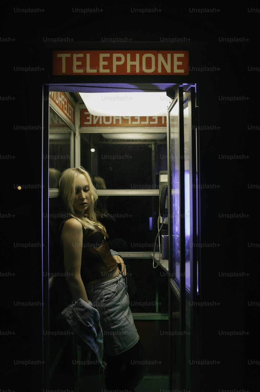 Una mujer parada frente a una cabina telefónica