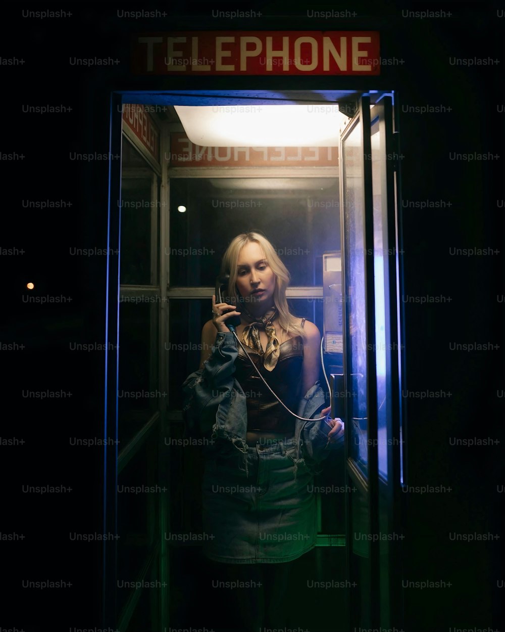 Una mujer está parada en una cabina telefónica
