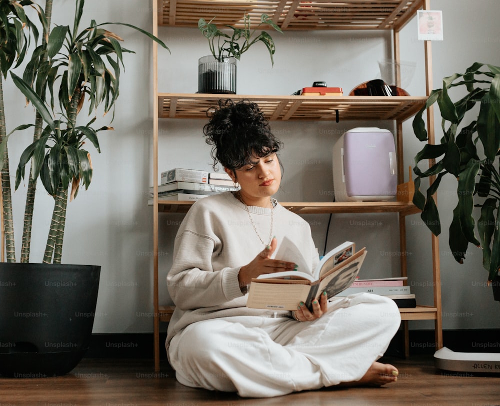 a woman sitting on the floor reading a book