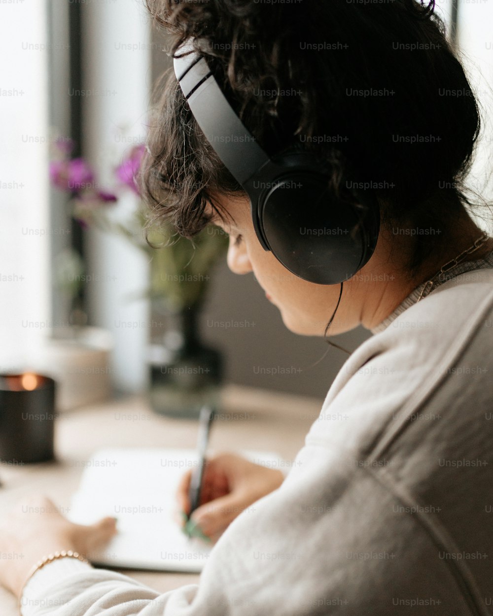 a woman wearing headphones writing on a notepad