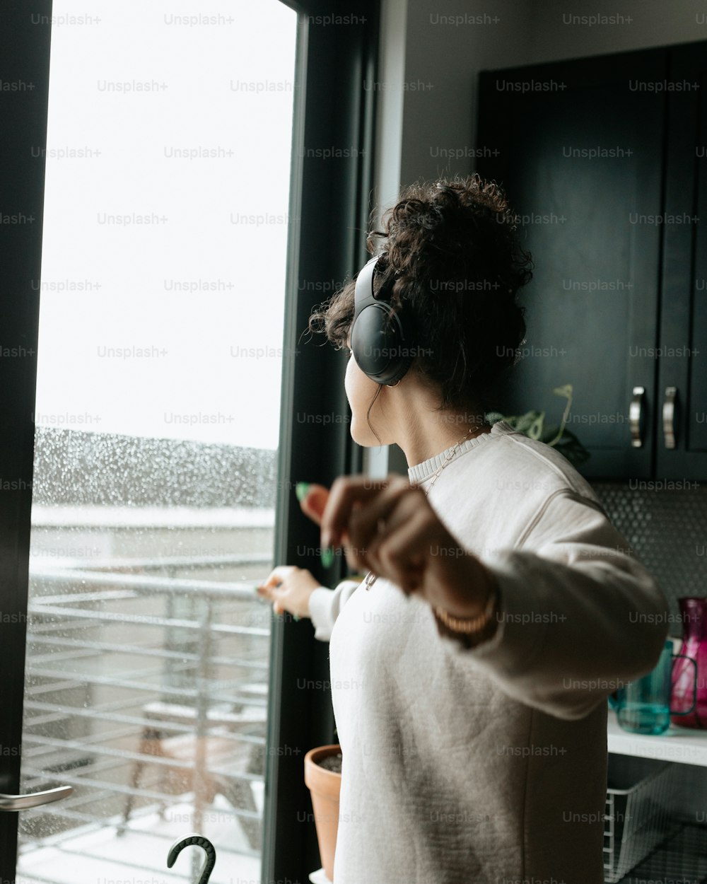 a woman wearing headphones standing in front of a window