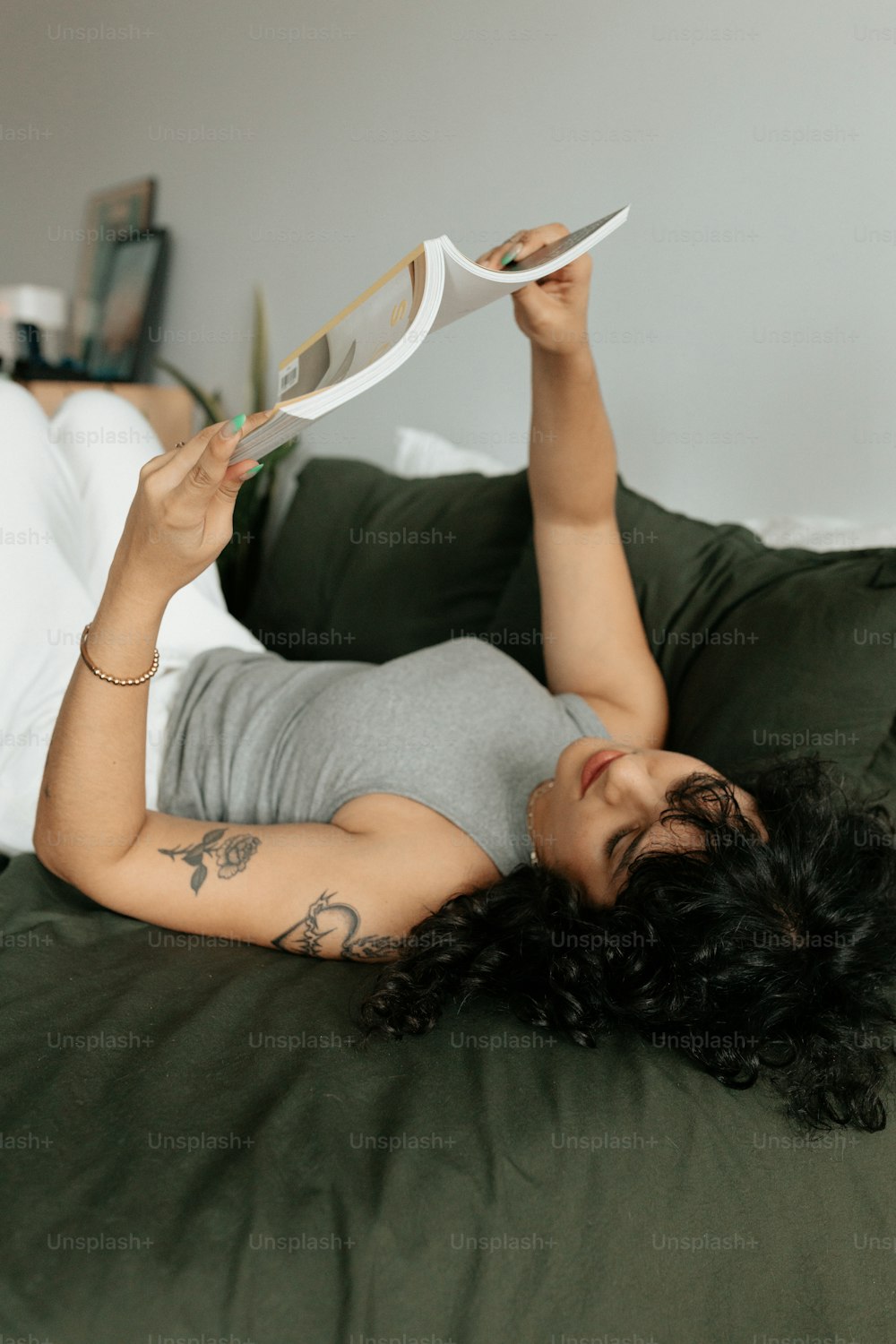 uma mulher deitada em uma cama lendo um livro