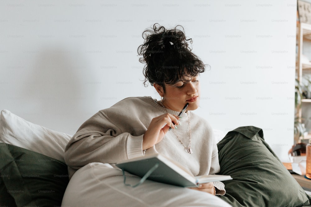 a woman sitting on a bed with a notebook in her hand