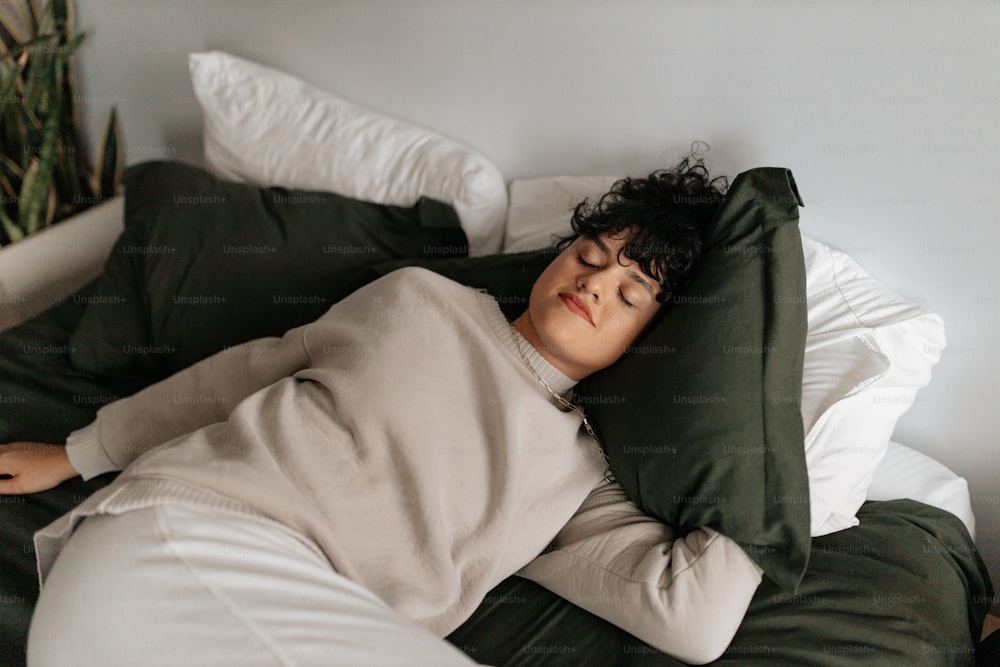 a person laying on a bed with a green pillow