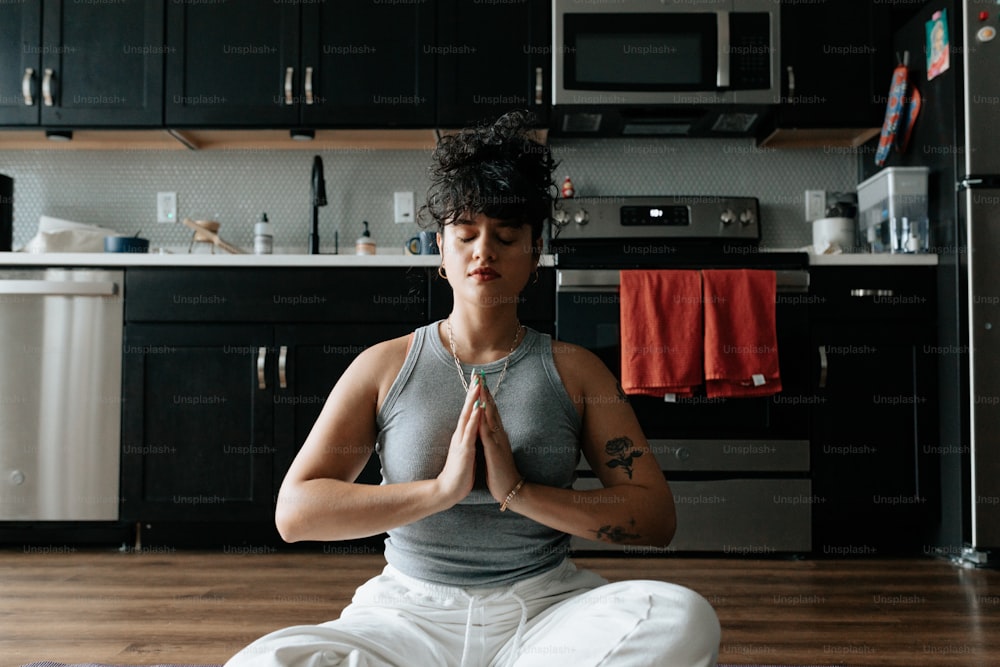 a woman sitting in a yoga position in a kitchen