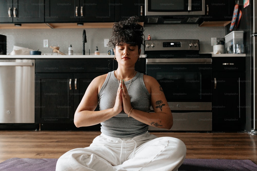 uma mulher sentada em uma posição de ioga em uma cozinha