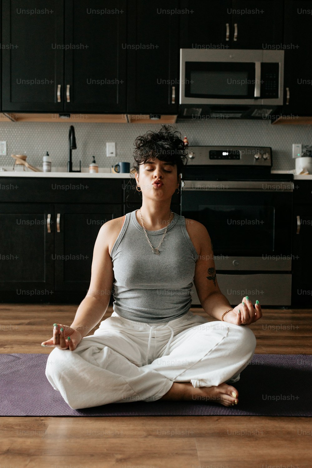 a woman sitting on a yoga mat in a kitchen