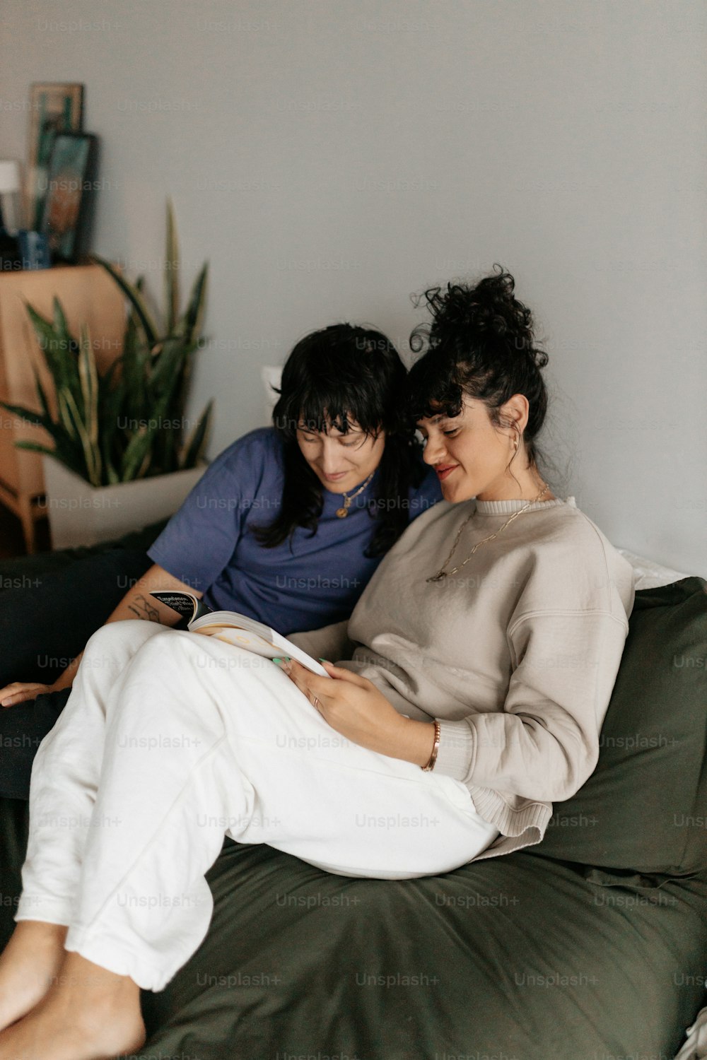 a couple of women sitting on top of a green couch