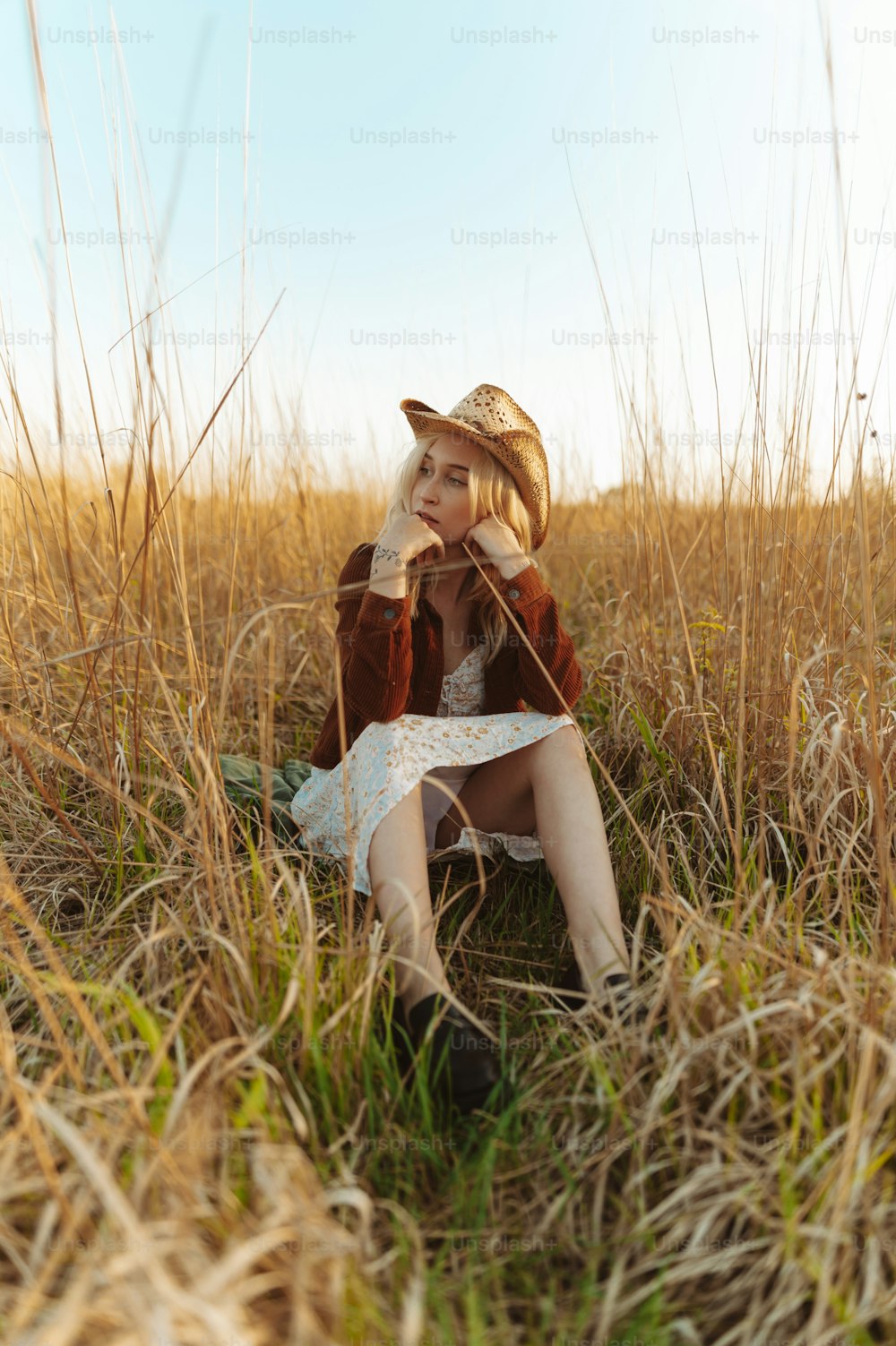 uma mulher sentada em um campo de grama alta