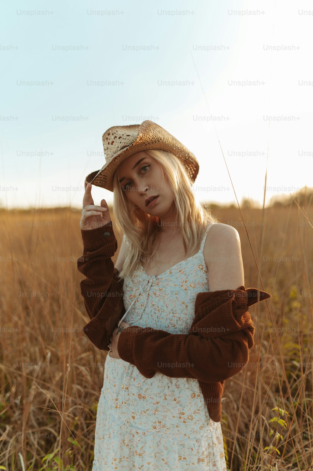 a woman standing in a field wearing a hat