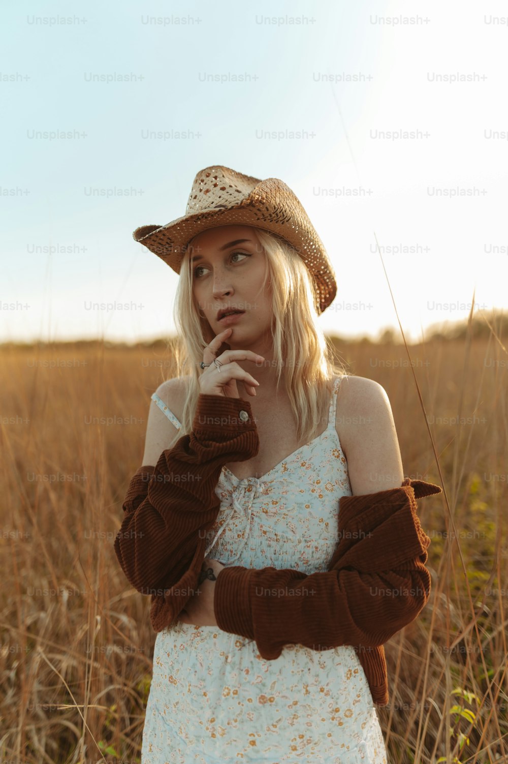 a woman standing in a field with a hat on her head