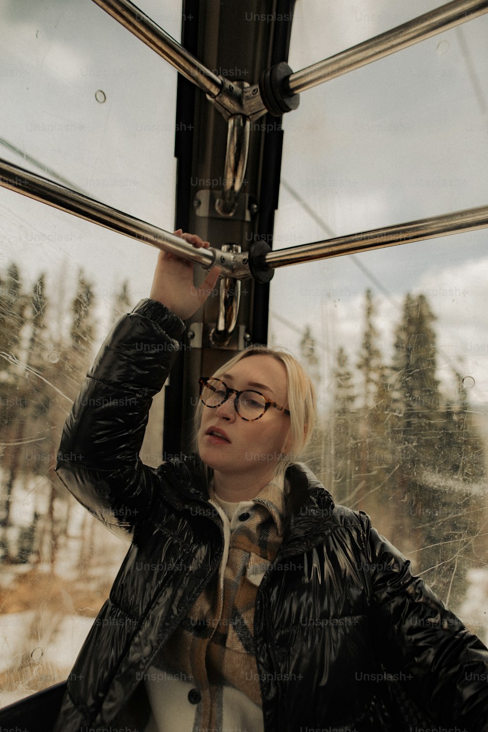 a woman in a black jacket and glasses on a train