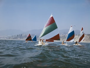 a group of people riding sailboats on top of a body of water