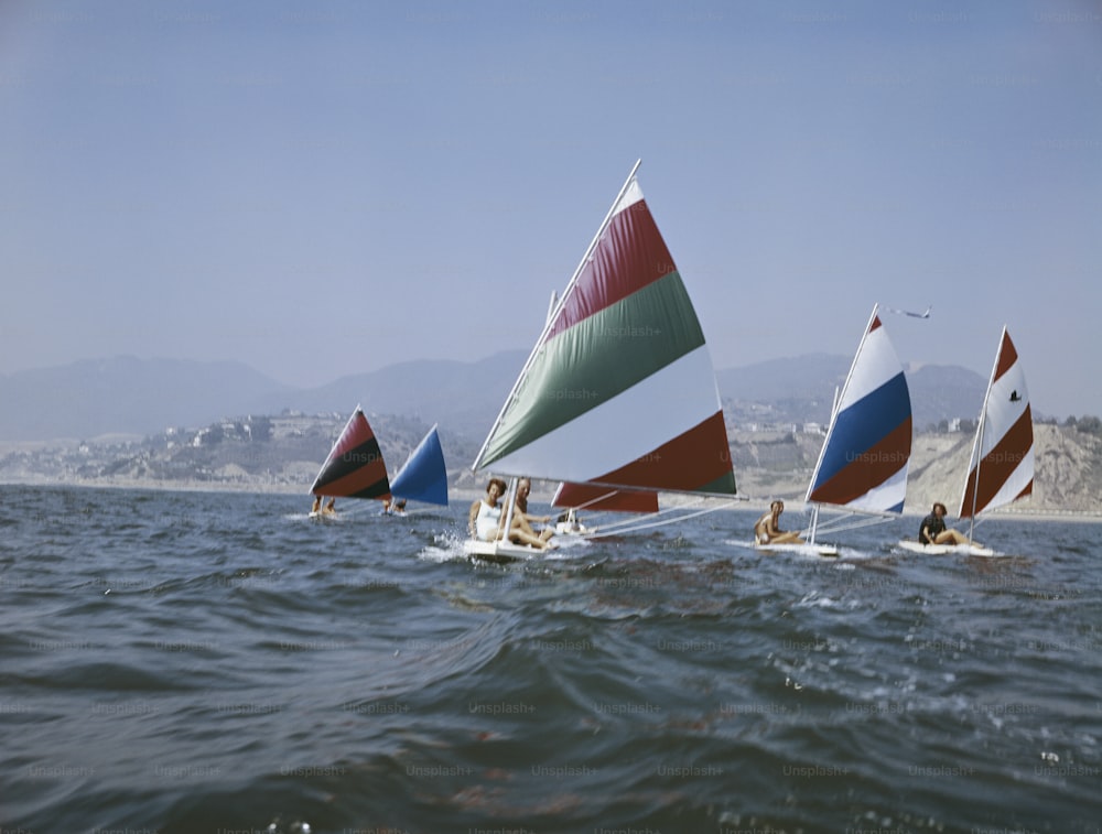 a group of people riding sailboats on top of a body of water