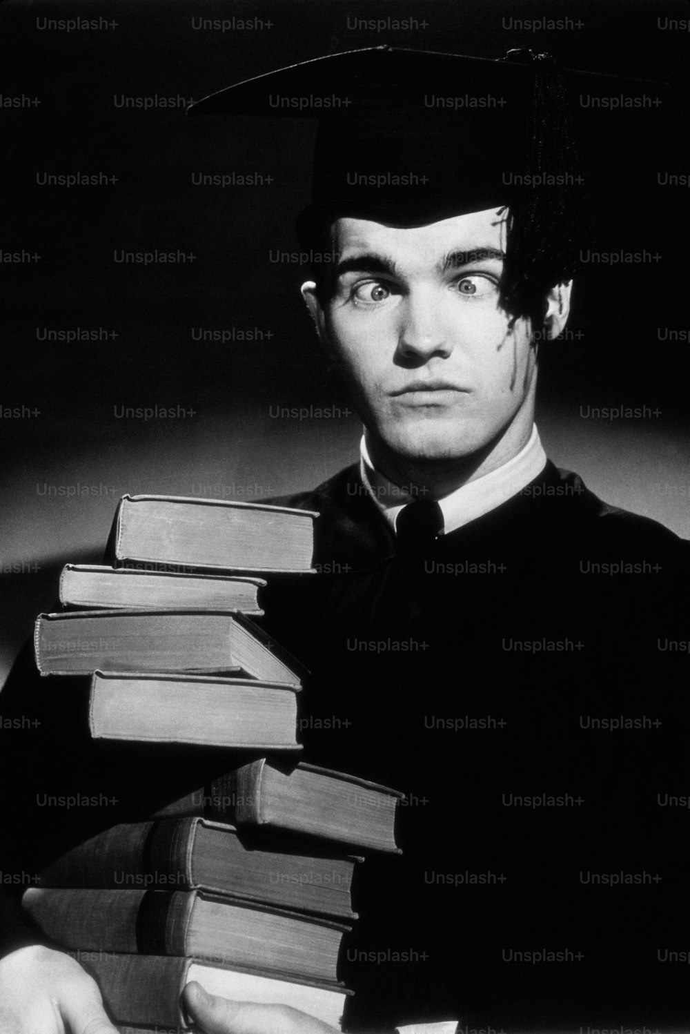Un hombre con una gorra y una bata sosteniendo una pila de libros