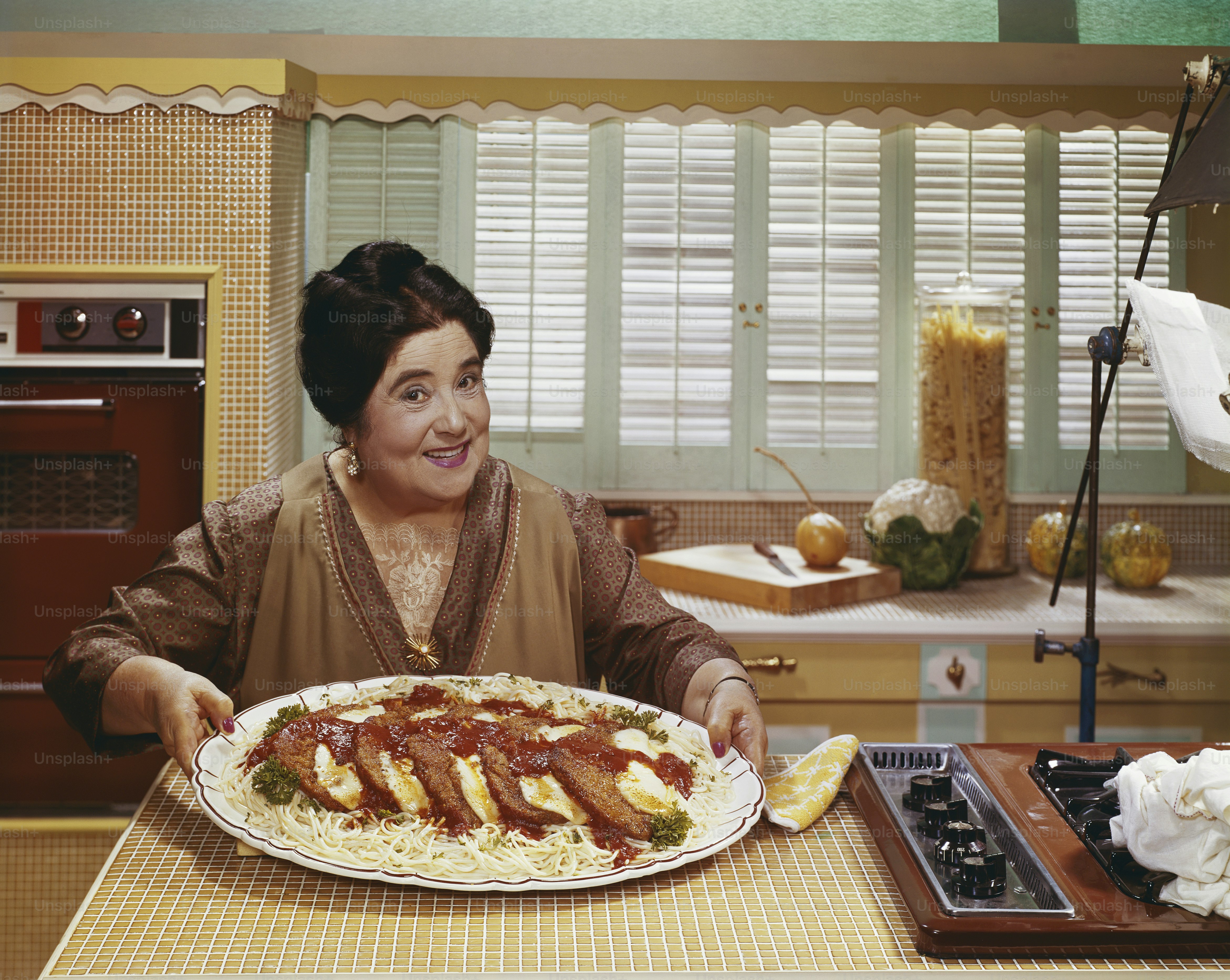 A woman holding a plate of food in a kitchen photo – Plate Image on ...