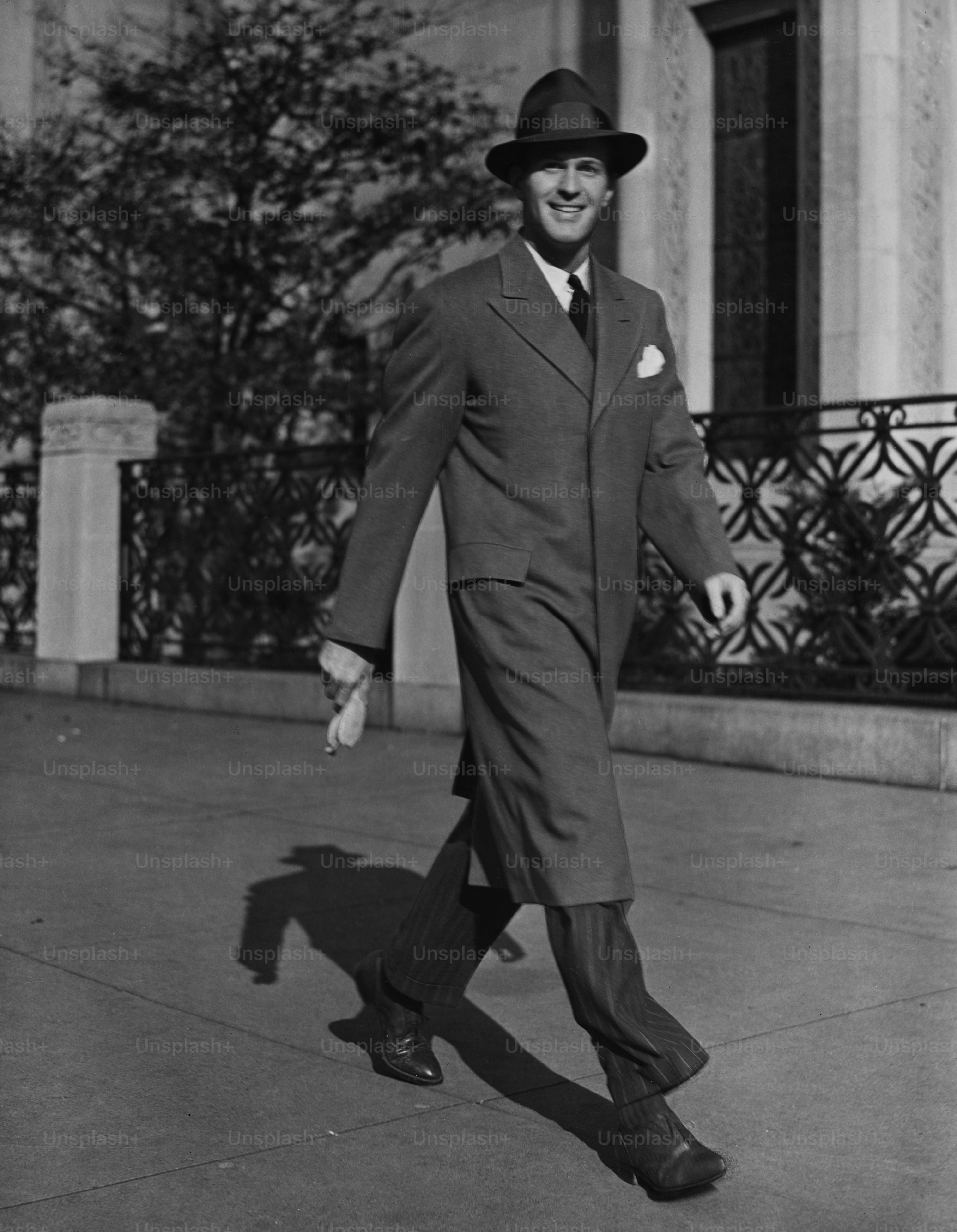 A businessman wearing suit, long coat and fedora walking on the street, US, circa 1950s. (Photo by George Marks/Retrofile/Getty Images)