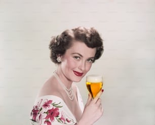 Eine Frau in einem weißen Kleid, die ein Glas Wein hält