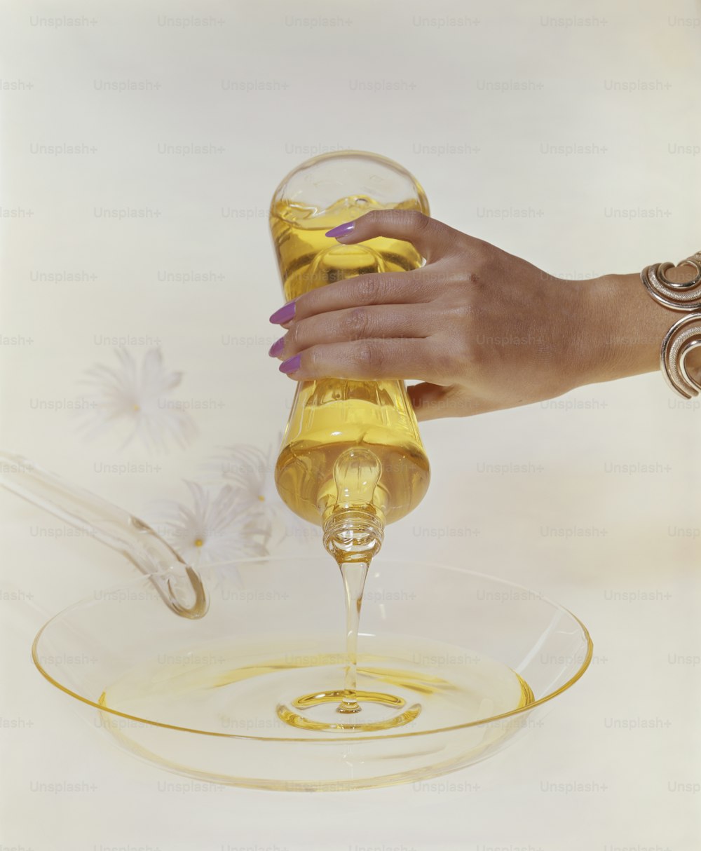 a woman is pouring oil into a glass