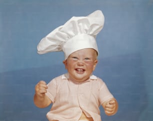 a baby wearing a chef's hat sitting down