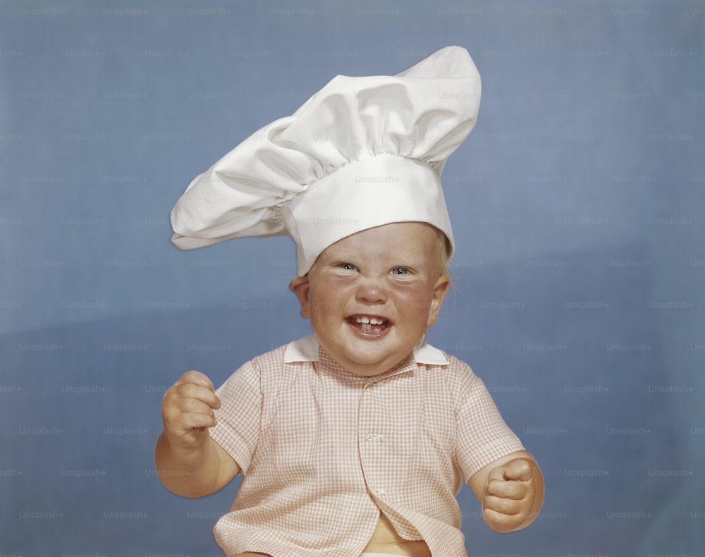 a baby wearing a chef's hat sitting down