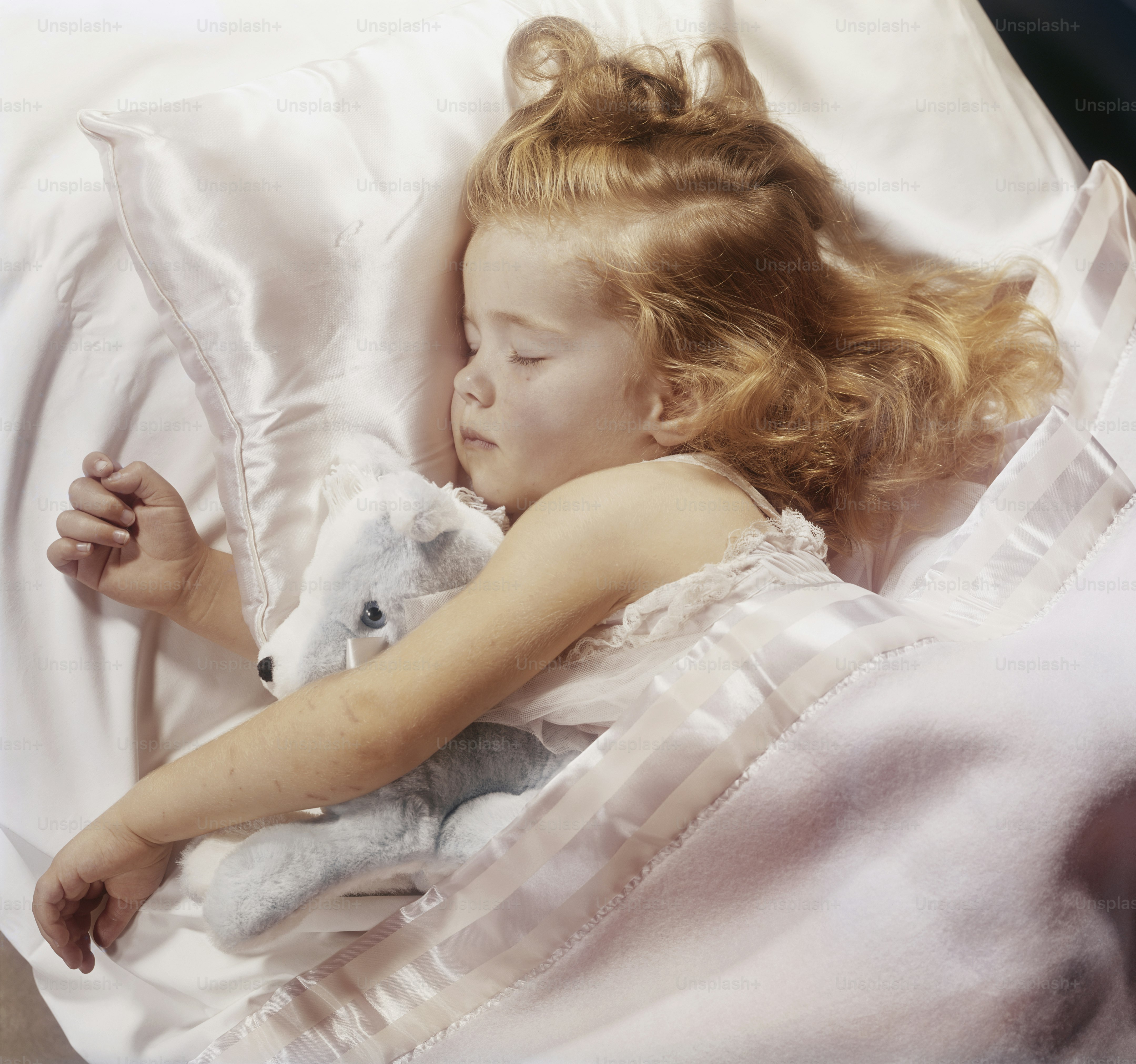 Foto Una niña acostada en una cama con un oso de peluche – Dormido ...