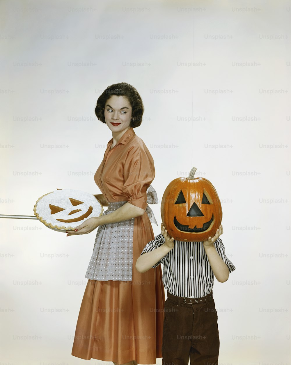 a woman holding a plate with a carved pumpkin on it