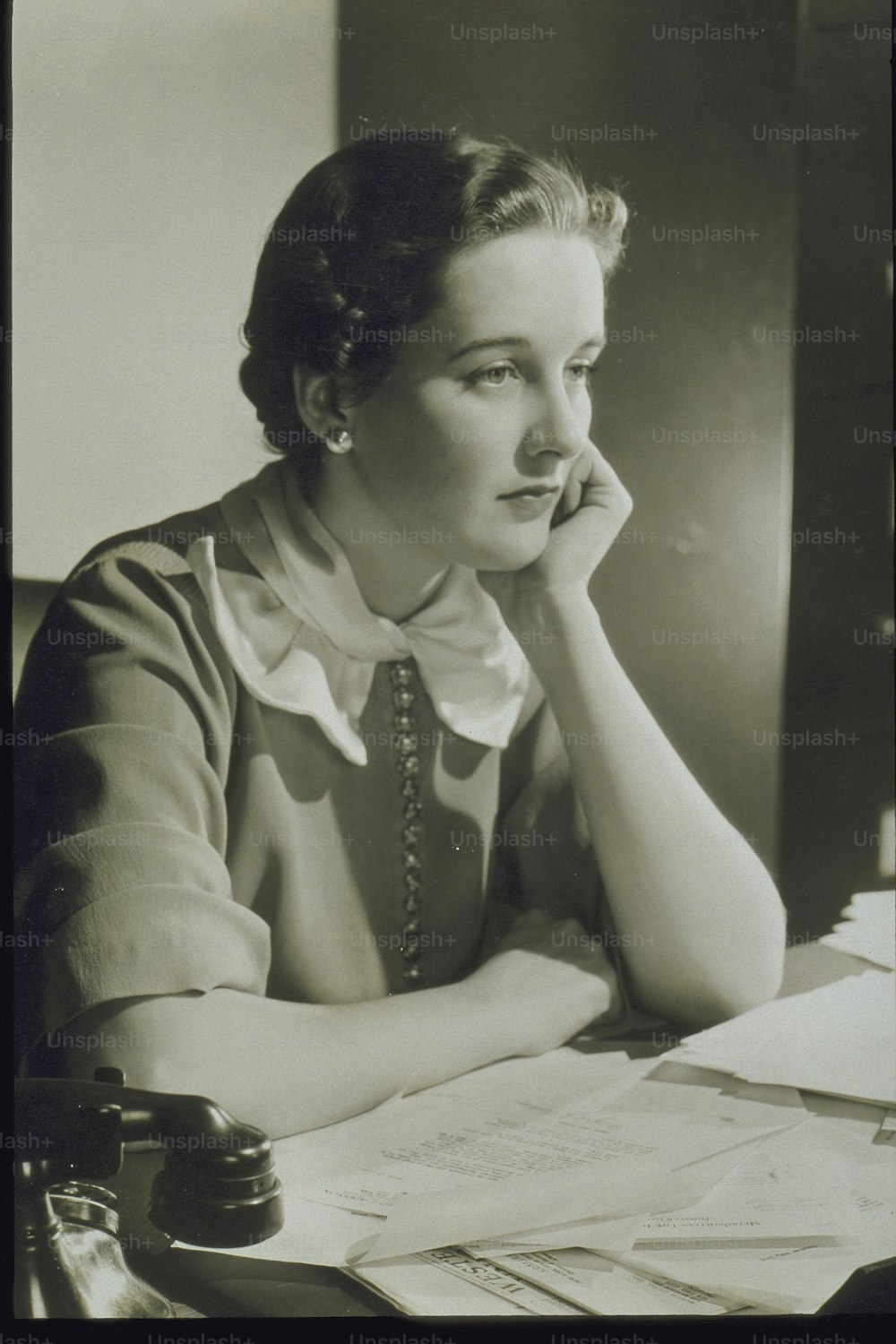 Una foto en blanco y negro de una mujer sentada en un escritorio