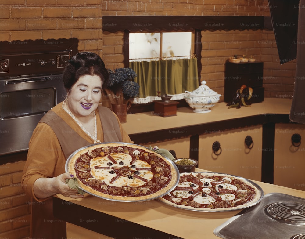 Eine Frau, die eine Pizza auf einer Theke hält
