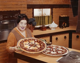 a woman holding a pizza on top of a counter