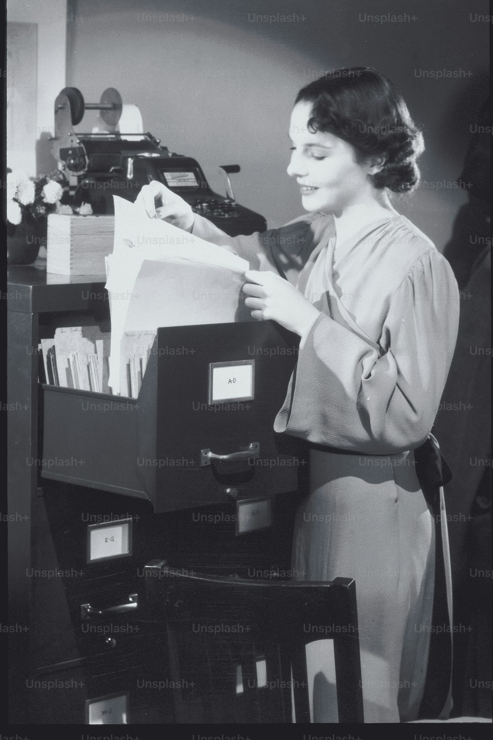 a woman is looking through a file cabinet