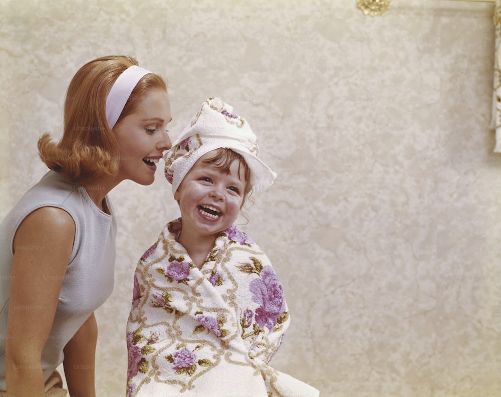 a woman standing next to a little girl in a bathrobe