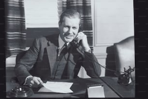 Ein Mann, der an einem Schreibtisch sitzt und telefoniert