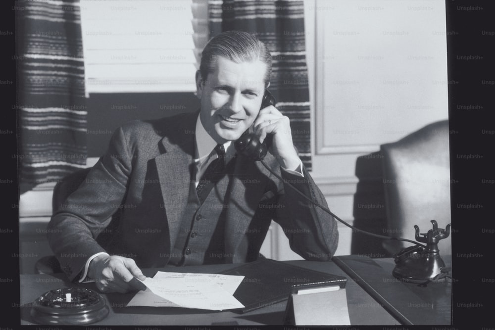 a man sitting at a desk talking on a phone