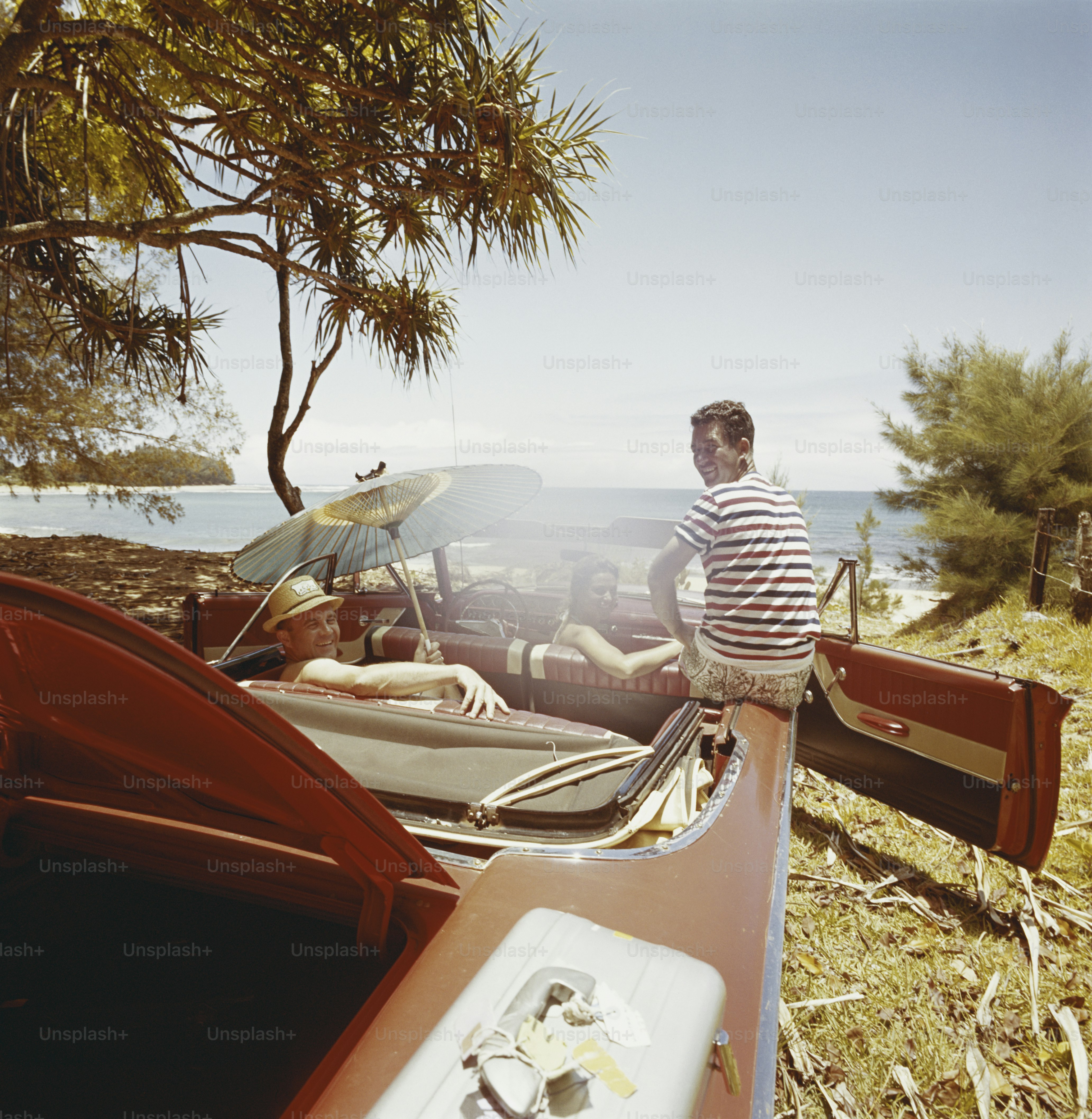 a man sitting on the hood of a red car